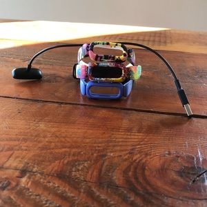 Fitbit with three bands and a charger.